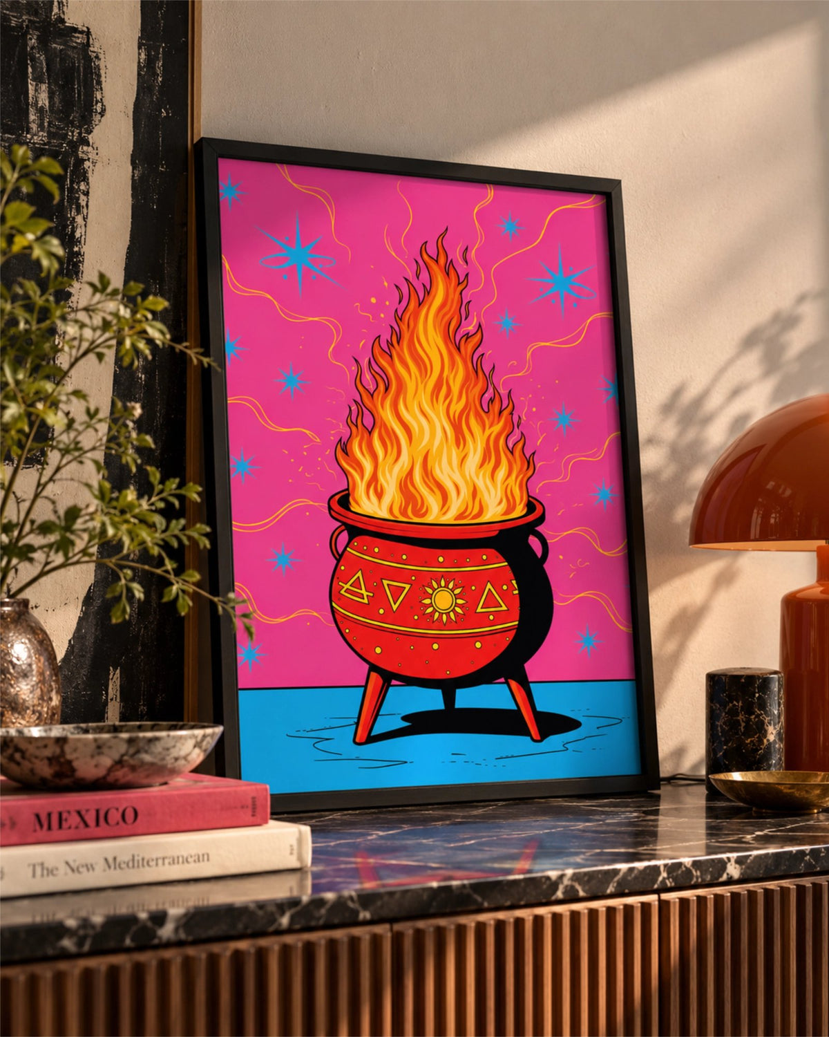 Affiche Hot Spell en cadre noir posée sur un buffet en marbre près d’une lampe orange et de plantes d’intérieur