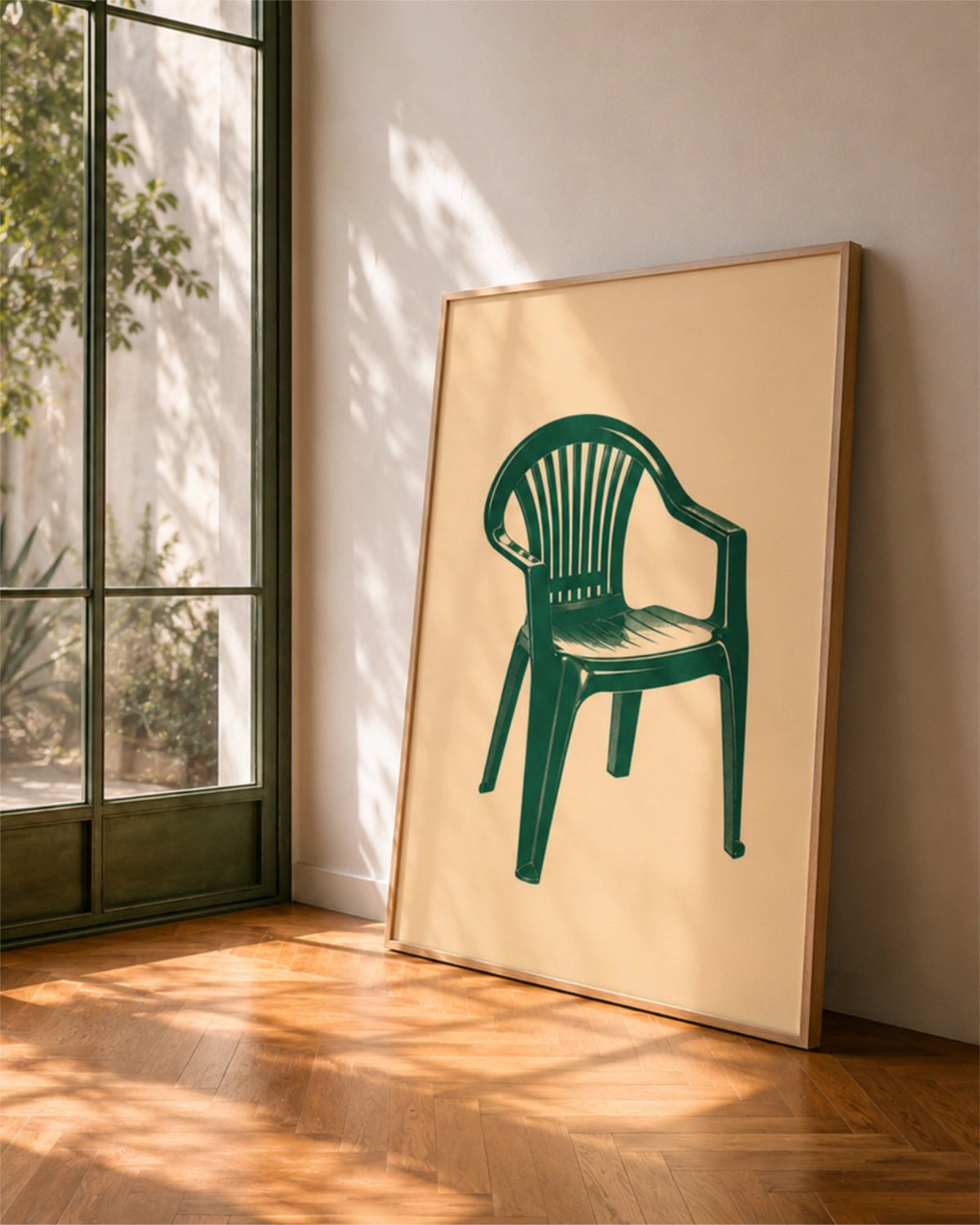 Affiche Monobloc en cadre en bois naturel posée près d’une grande fenêtre, avec une chaise en plastique verte sur fond crème