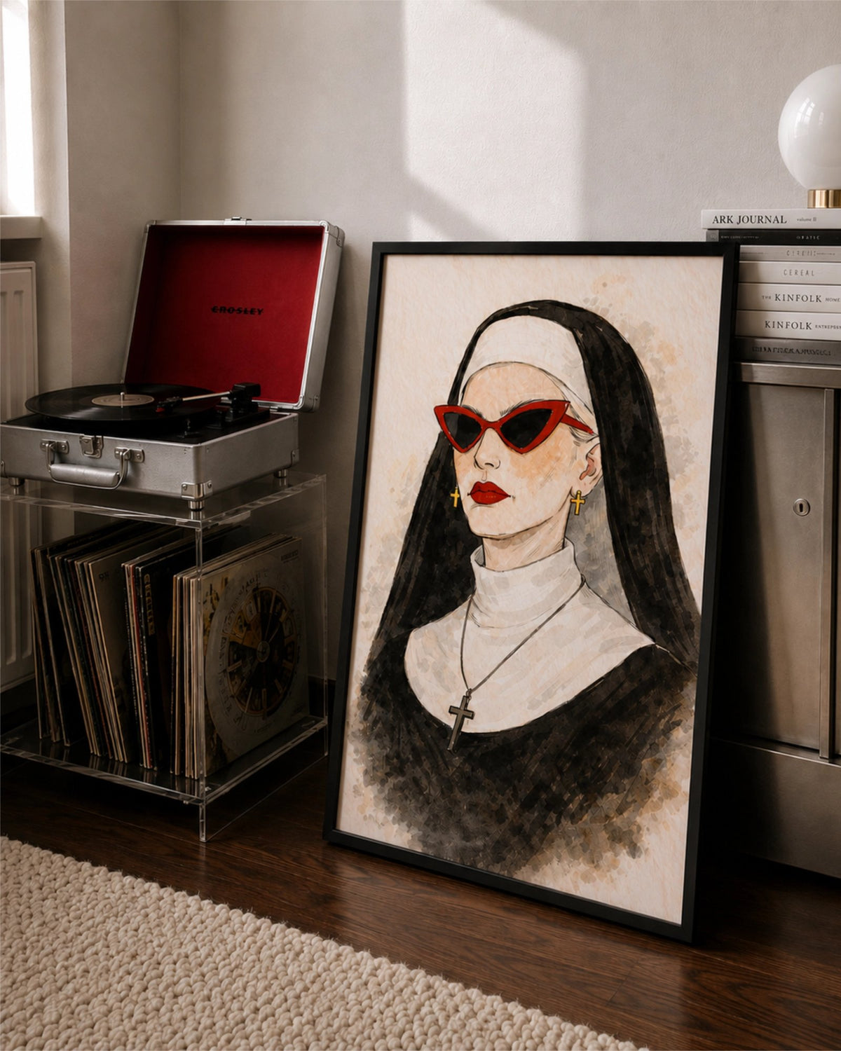 Bad Habit art print in a black frame leaning against a wall next to a record player and vinyl records, showing a nun in red cat-eye sunglasses and red lipstick.