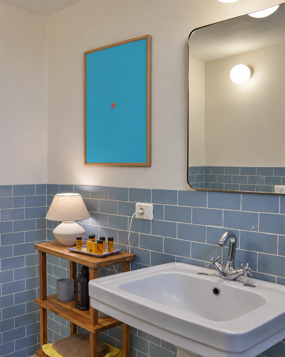 Affiche Do Not Disturb encadrée au-dessus d’une étagère en bois dans une salle de bains aux carreaux bleu pâle, avec une minuscule silhouette sur une bouée rose.