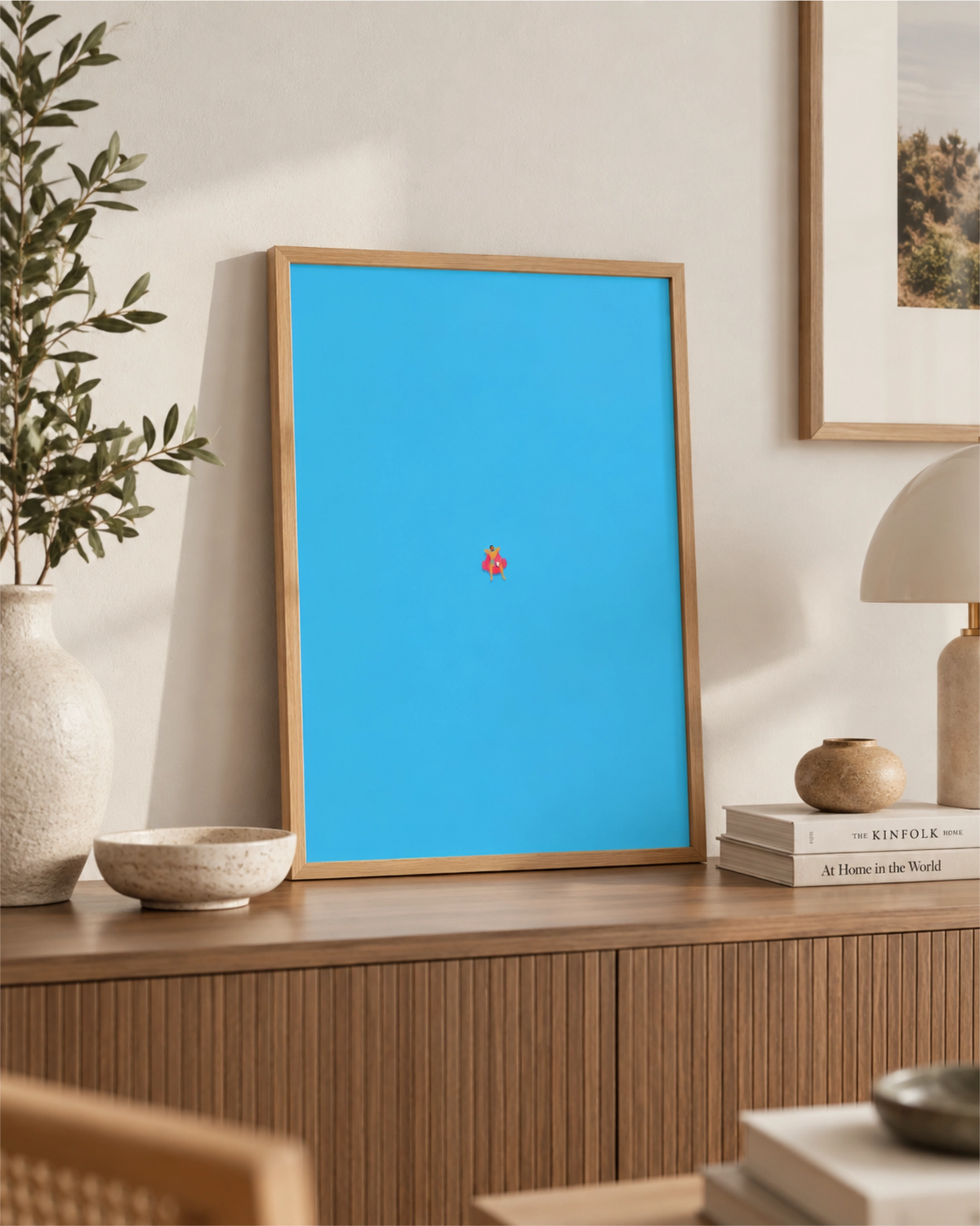 Affiche Do Not Disturb dans un cadre en bois naturel posée sur un buffet en bois, avec une minuscule silhouette flottant dans une eau bleu vif.
