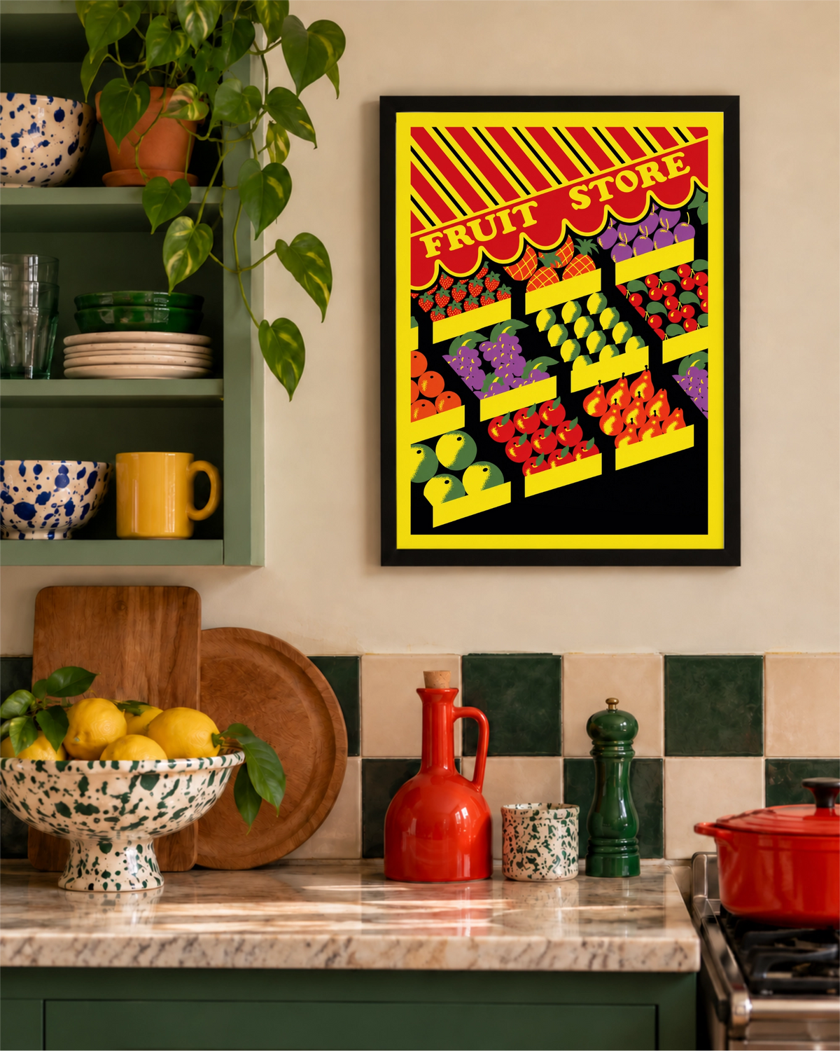 Fresh Pick art print in a black frame on a warm kitchen wall above a marble counter with green cabinetry, lemons and red cookware.