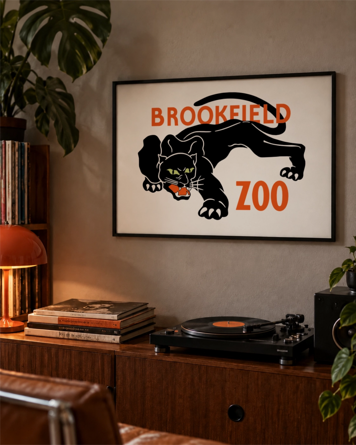 Night Prowl art print in a black frame above a record player and wooden console with an orange lamp, vinyl records and houseplants.