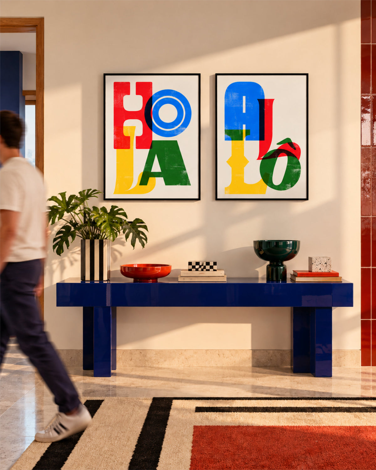Two framed colourful typographic posters reading Hola and Allô displayed above a blue console table in a warm interior