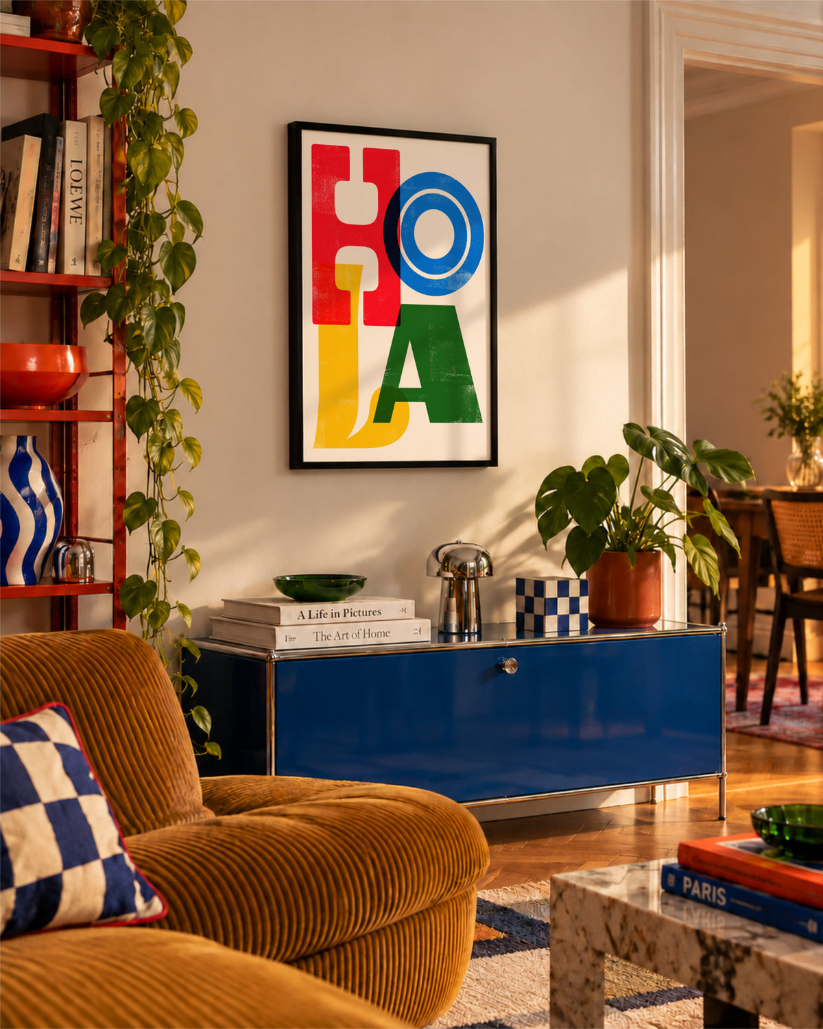 Framed Hola typographic poster above a blue sideboard in a warm, eclectic living room