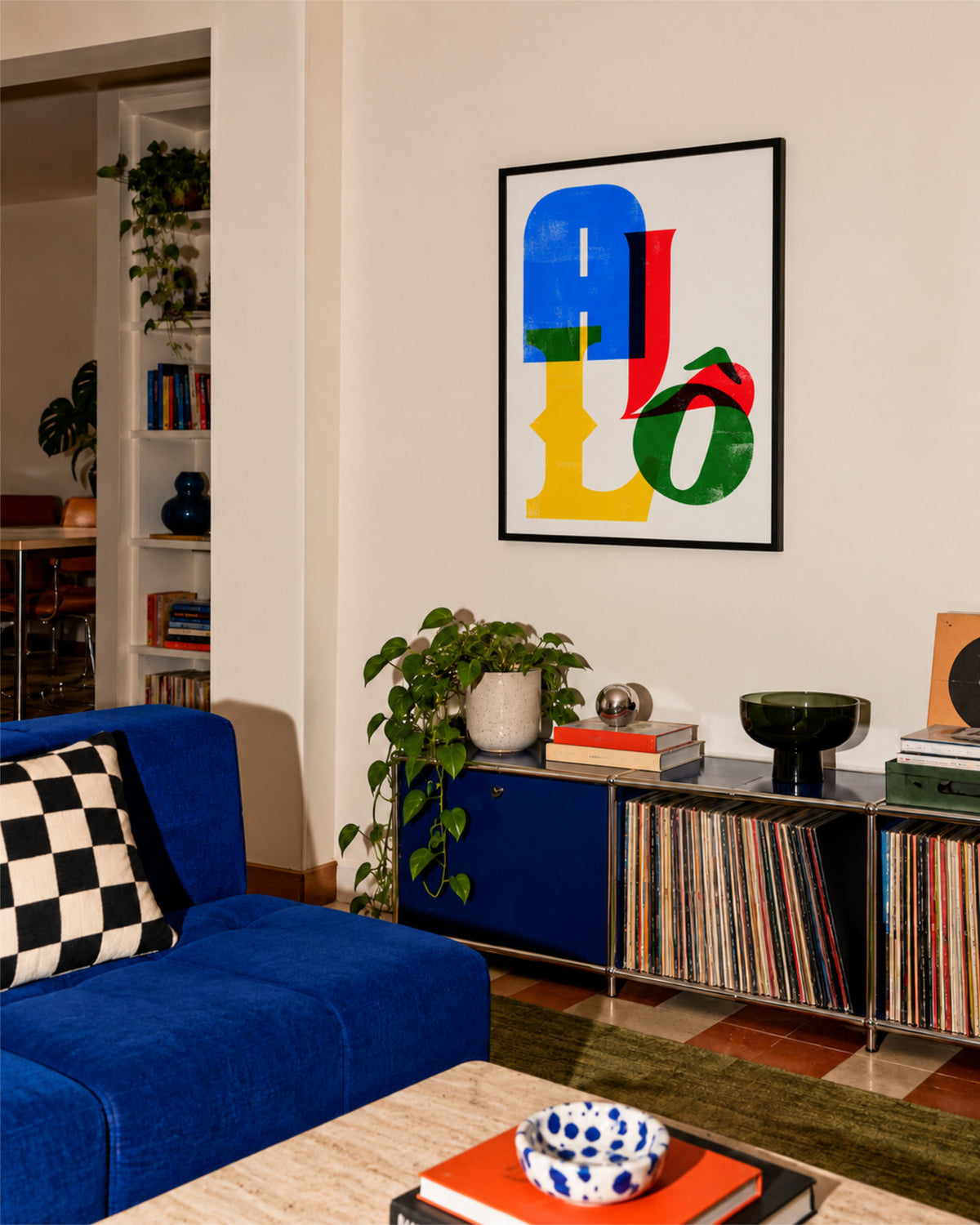 Framed Allô typographic poster above a blue record cabinet in a warm living room